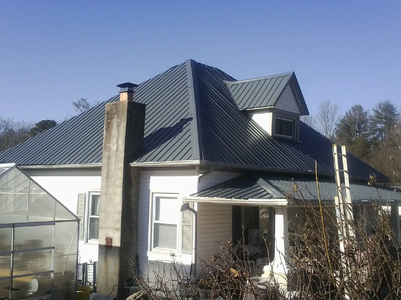 Dark blue standing seam metal roof on a white farmhouse with dormer — Slate & Tile Roof Repair by Roofing Brothers in Merrimack