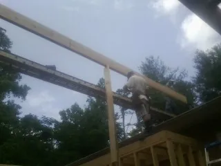 Carpenter setting a ridge beam over a new addition frame — Ice Dam Removal by Roofing Brothers in Merrimack