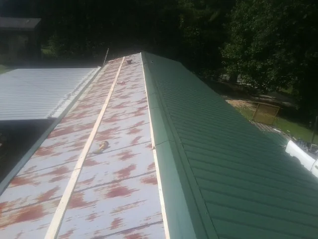 Old rusted panels beside newly installed green metal roofing — Wind Damage Roof Repair by Roofing Brothers in Merrimack