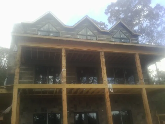 Dormers and porch framing on a large log home under construction — Roof Coating work by our crew in Merrimack