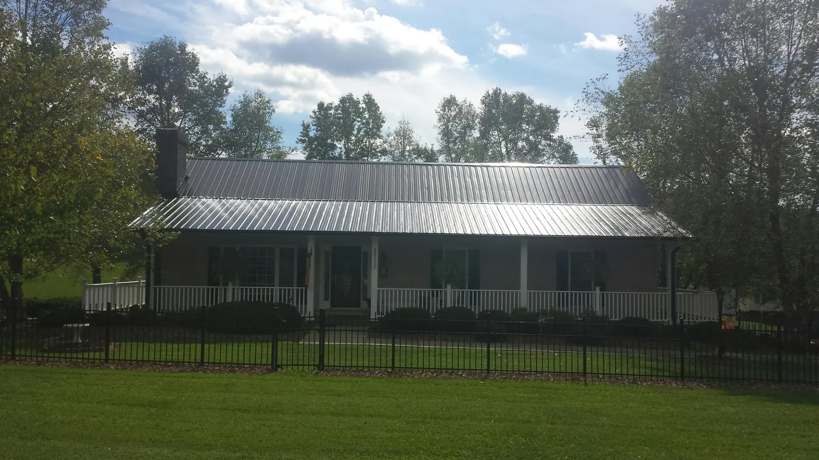 Gray metal roof on a brick ranch with a full width front porch — Gutter Guard Installation work by our crew in Merrimack