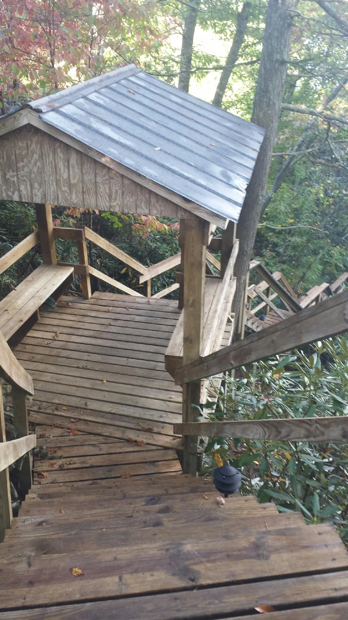 Metal roofed shelter over wooden steps on a wooded walkway — Skylight Repair & Installation work by our crew in Merrimack