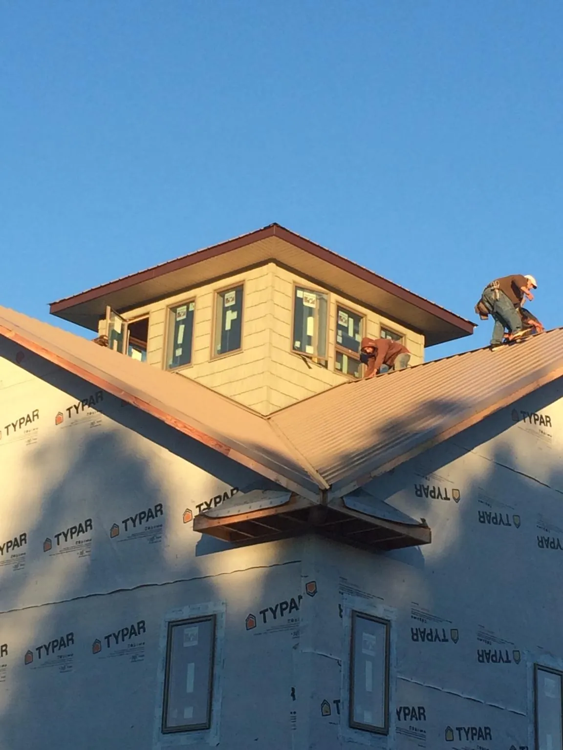 Roofers working around a rooftop cupola on a new metal roof at sunset — Roof Waterproofing in Merrimack by Roofing Brothers